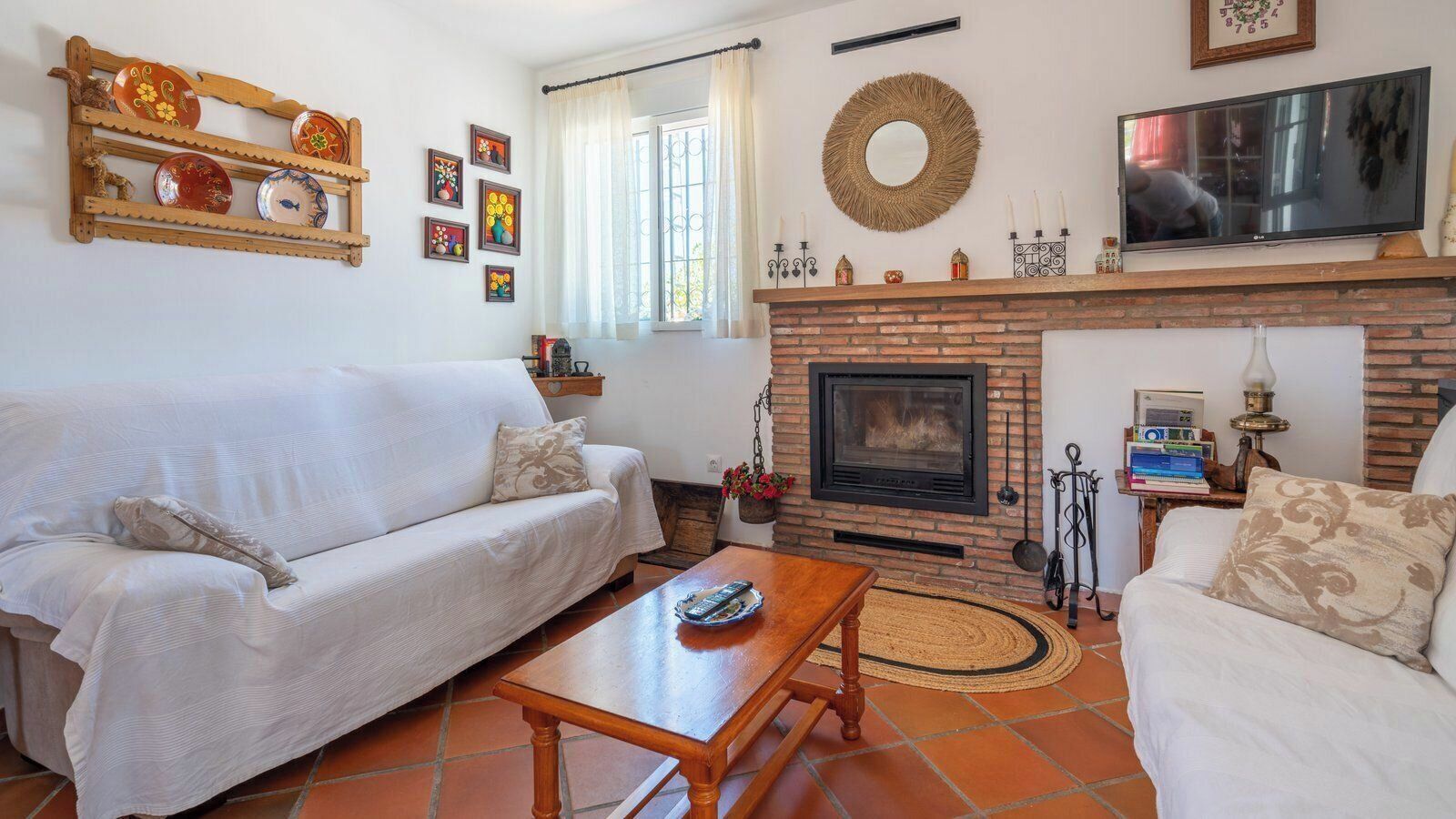 Una sala de estar con sofá, mesa de centro, chimenea y televisor.