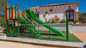 Playful playground area adjacent to the building, featuring a green slide and climbing structure.
