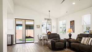 A spacious living room with a fireplace, a dining area with a table and chairs, and a sliding glass door leading to a patio. - Hyatt Home Pet Friendly! Community pool and hot tub! (Washington)