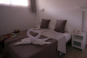 A hotel room with a bed, a nightstand, a mirror, and a window with curtains. - Apartamentos Livvo Tarahal (San Bartolomé de Tirajana)
