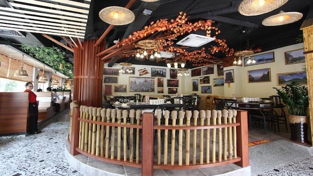 A restaurant interior with a central bamboo structure, hanging lights, and framed pictures on the walls. - J.S Fashion Hotel (Zhuhai)
