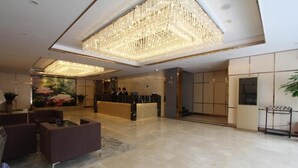 A spacious lobby with a large chandelier, a reception desk, and seating areas. - J.S Fashion Hotel (Zhuhai)