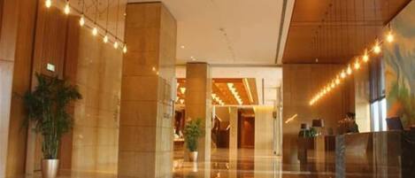 A spacious lobby with a polished floor, large pillars, and string lights.