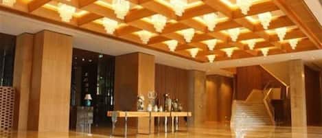 A lobby with a polished floor, a reception desk, and a staircase.