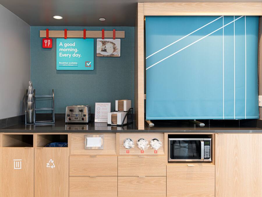 A modern kitchen with a microwave, toaster, and a breakfast sign indicating availability.