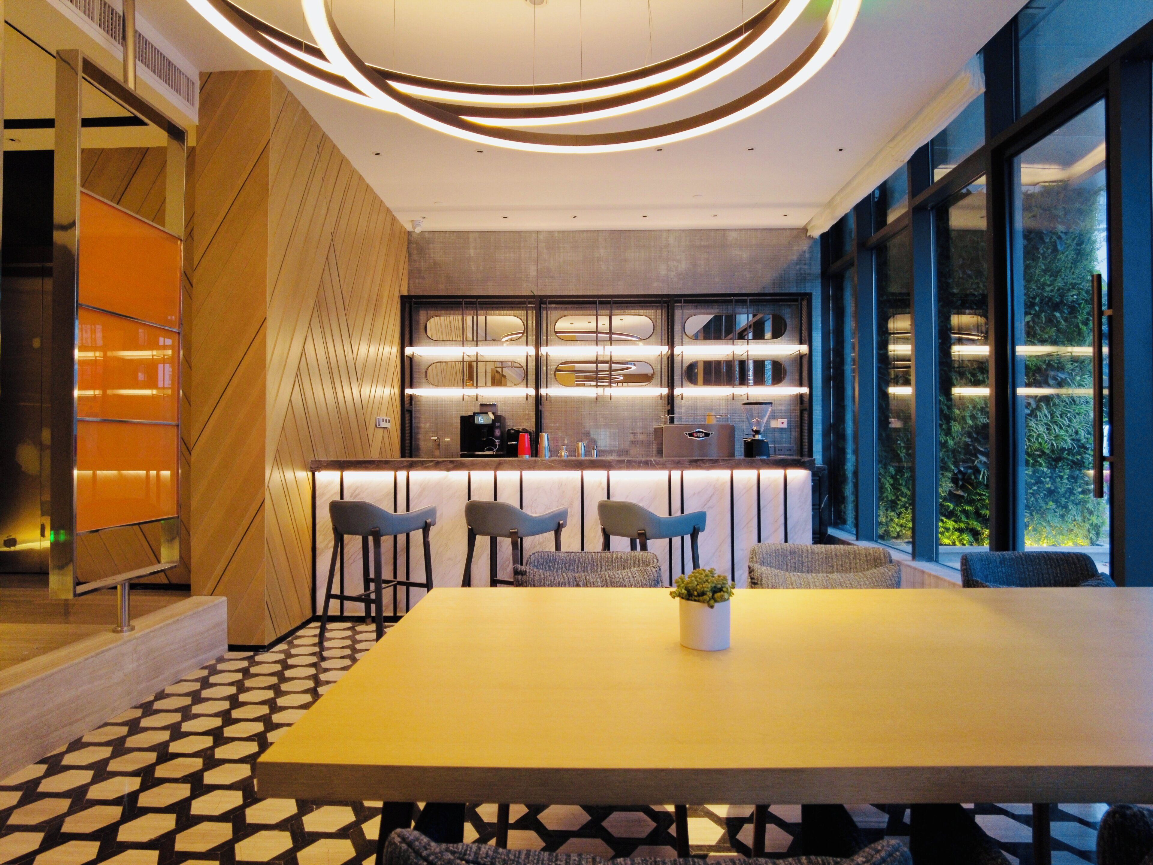 A modern interior with a long table, bar seating, and a kitchen area with a view.