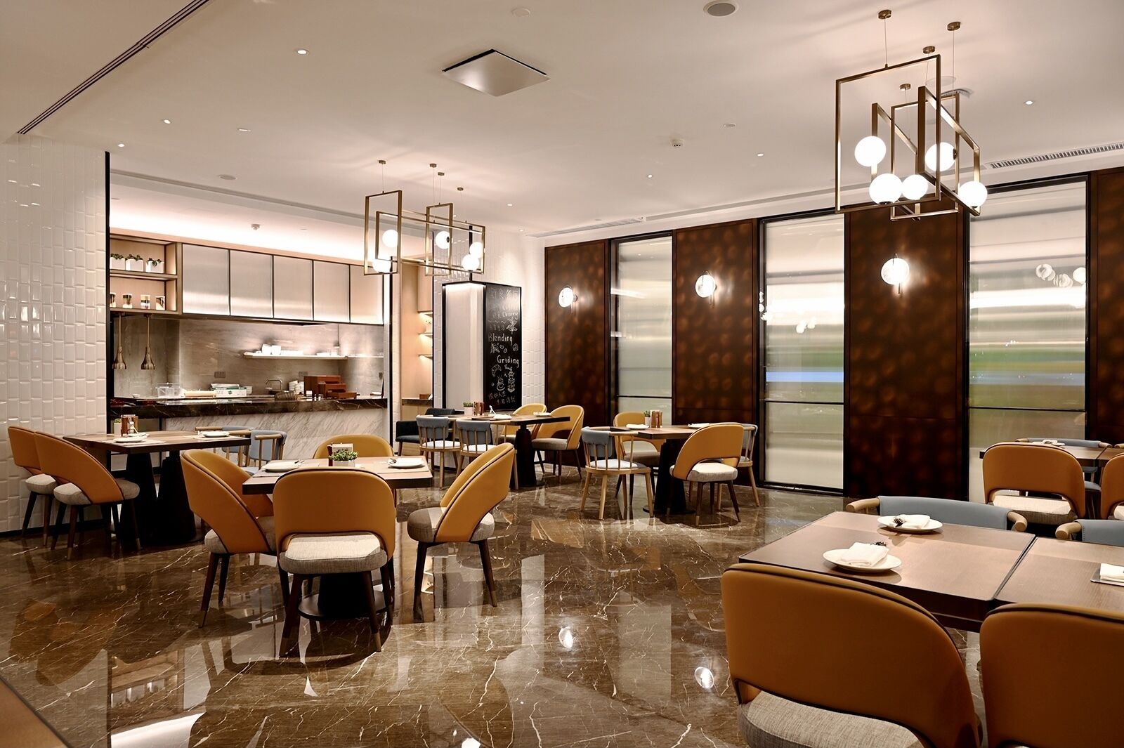 A modern restaurant with marble flooring, yellow chairs, and a large window offering a view.