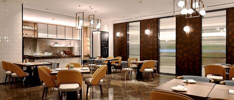 A modern restaurant with marble flooring, yellow chairs, and a large window offering a view.