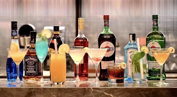 A variety of cocktails and liquor bottles on a bar counter.