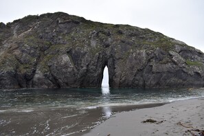 A rocky coastal landscape with a natural arch formation.