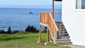 A coastal building with a wooden staircase leading to a deck overlooking the sea. - Beautiful Ocean View Home on the Majestic Oregon Coast The Blue Pelican (Brookings)