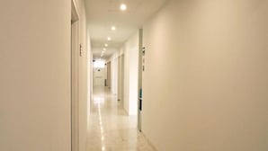 A long, narrow hallway with a polished floor and white walls. - Hit Hoteles Aeropuerto Puebla (Huejotzingo)