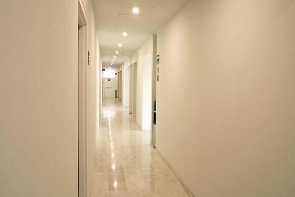Un long couloir étroit, doté d’un plancher ciré et de murs blancs.