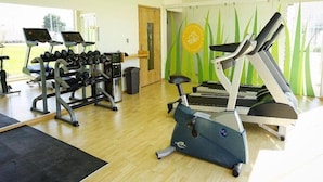 A gym with treadmills, an elliptical, and a weight rack. - Hit Hoteles Aeropuerto Puebla (Huejotzingo)