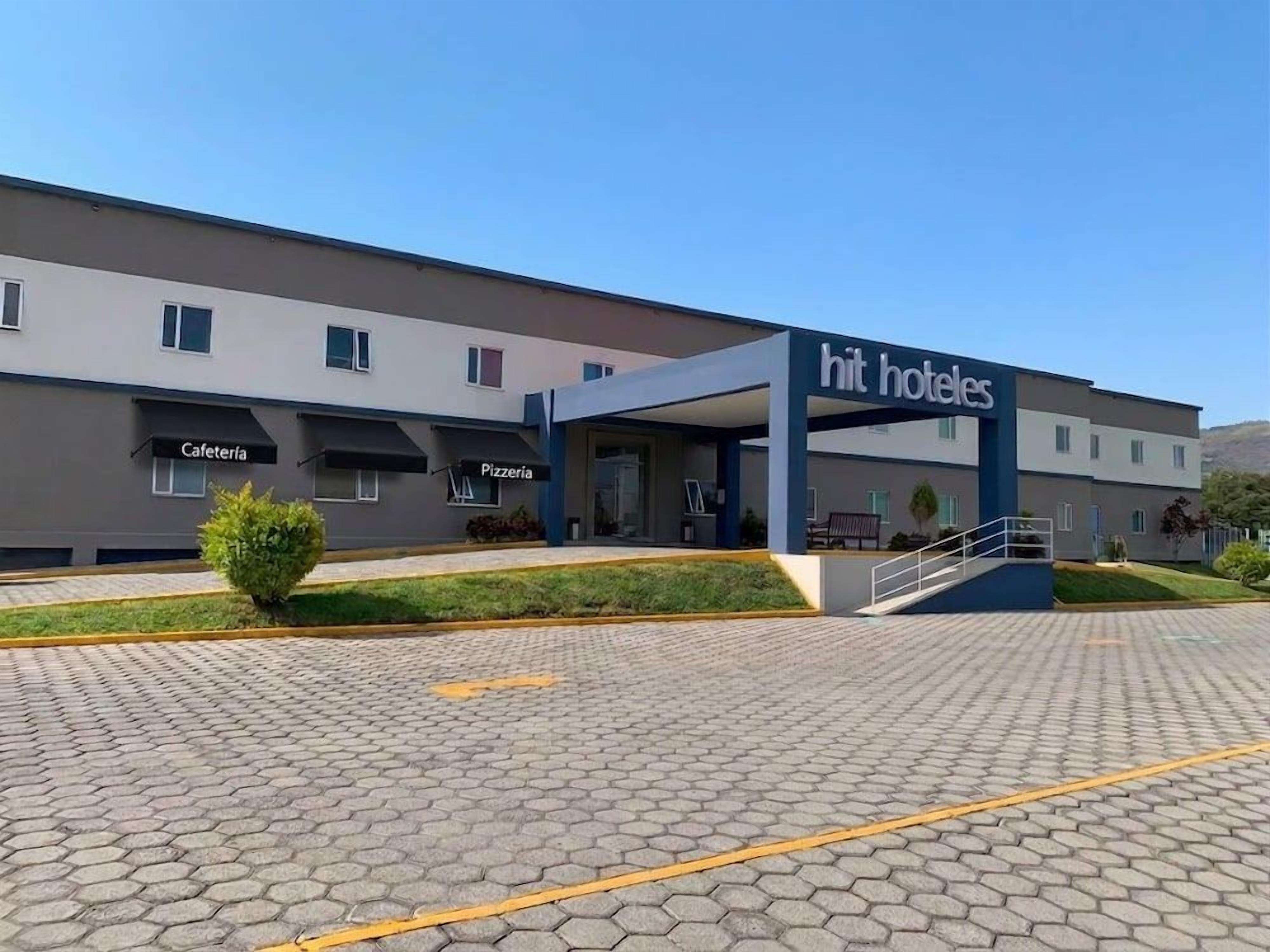 Un hotel con entrada cubierta, un área de patio y un letrero que indica cafetería y pizzería.