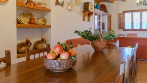 Una mesa de comedor de madera con un cuenco decorativo de fruta y una planta en maceta.
