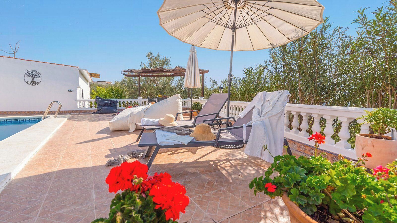 Ein Poolbereich mit Liegestühlen, einer Pergola und Kübelpflanzen.
