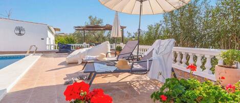 Ein Poolbereich mit Liegestühlen, einer Pergola und Kübelpflanzen.
