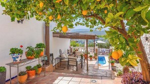 Un patio con mobiliario exterior, plantas en macetas y vistas al paisaje.