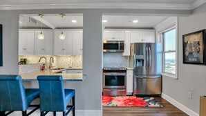 Una cocina moderna con armarios blancos, electrodomésticos de acero inoxidable y una zona de bar azul.