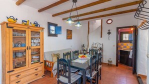 Un coin repas avec un buffet en bois, une table dressée pour quatre personnes et une fenêtre ornée de volets bleus.