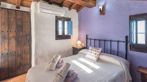 Une chambre à coucher avec un lit, des oreillers, une table de chevet, une lampe et une armoire.