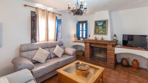 Un salon avec un canapé, une cheminée, un téléviseur et un tableau accroché au mur.