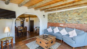 A cozy living room with a blue sofa, wooden coffee table, and a stone fireplace wall. - Villa Javier de Frigiliana by Ruralidays (Málaga)