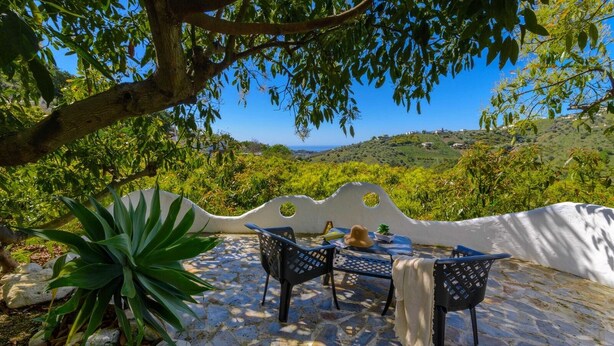 An outdoor patio with a table and chairs, surrounded by greenery and a scenic view of hills. - Villa Javier de Frigiliana by Ruralidays (Málaga)