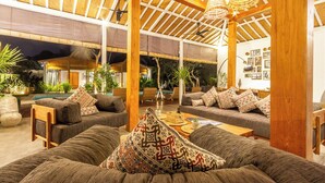 Amplio espacio interior con vigas de madera, asientos cómodos y una piscina al fondo.