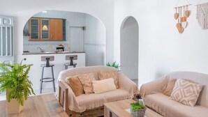 Una sala de estar moderna con dos sofás, una mesa de centro y una zona de comedor con una cocina al fondo.