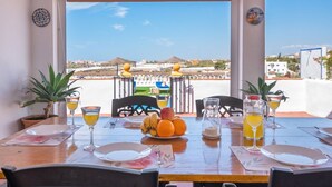 Una mesa de comedor dispuesta con platos, cubiertos, vasos y un frutero.