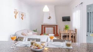 Una habitación de hotel con una cama, una mesa de comedor con sillas, un televisor y una chimenea.
