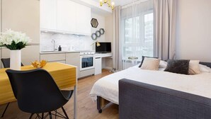 A modern hotel room with a bed, a dining area, and a kitchenette. - Modern Studio | Parking | Close to the Airport (Warszawa)