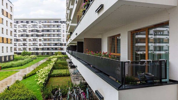 A modern apartment building with a balcony, a garden, and bicycles. - Modern Studio | Parking | Close to the Airport (Warszawa)