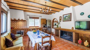 Un espacio de sala acogedor con una mesa de comedor preparada para cuatro personas, una chimenea y un televisor.