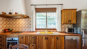 Una cocina con armarios de madera, horno empotrado, microondas y fregadero.