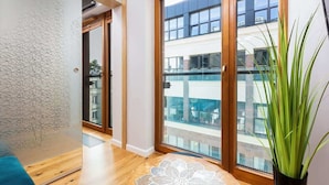 A modern room with a large window, a wooden floor, and a potted plant. - Modern Studio in the Center | Balcony | Close to Attractions (Warszawa)