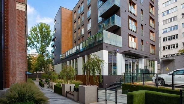 A modern multi-story building with balconies, a covered walkway, and a parking area. - Modern Studio in the Center | Balcony | Close to Attractions (Warszawa)