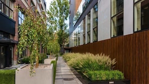 A modern building with a concrete pathway, green plants, and a wooden wall. - Modern Studio in the Center | Balcony | Close to Attractions (Warszawa)