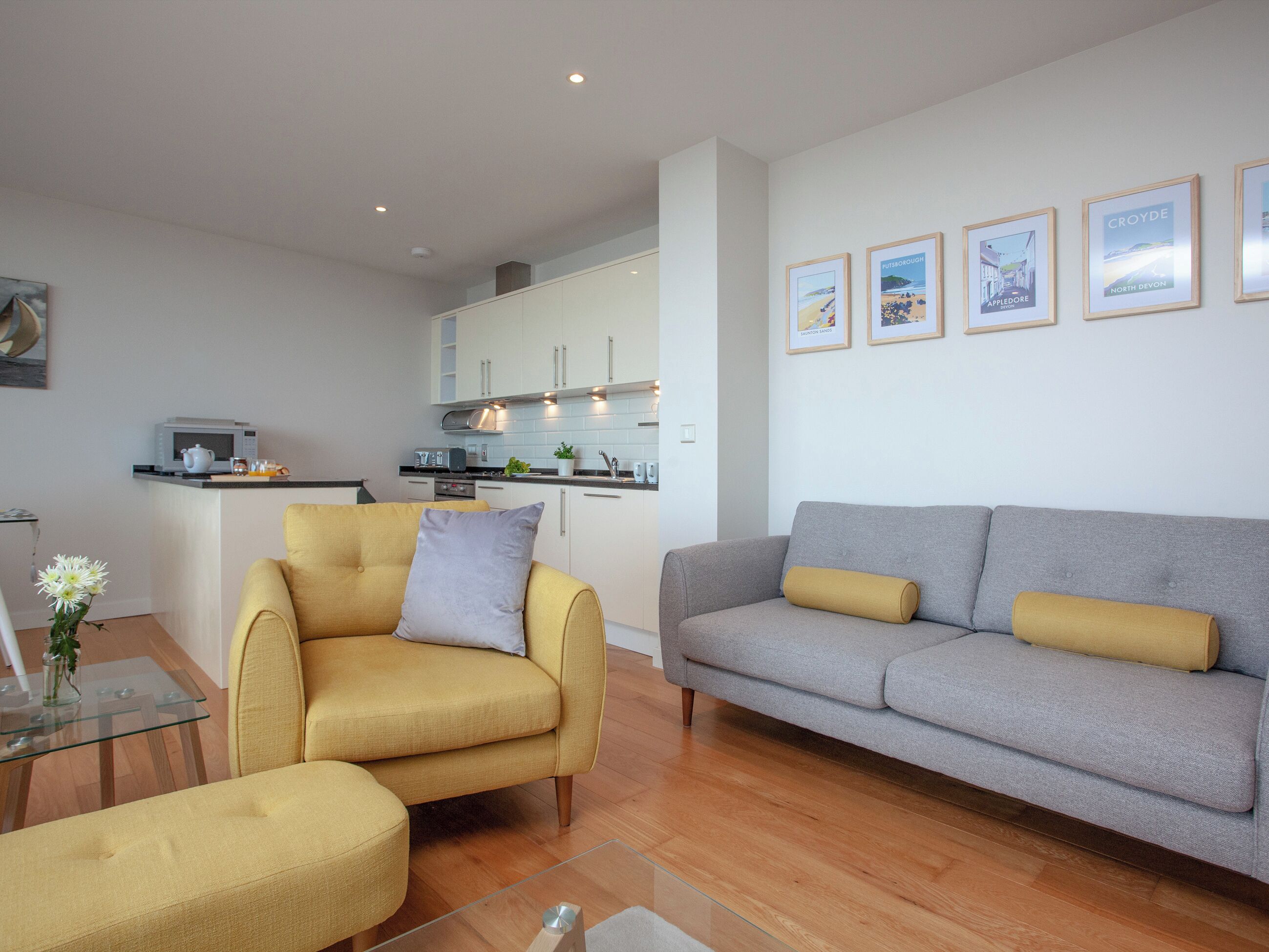 Uma sala de estar moderna com sofá, poltrona e mesa de centro de vidro.
