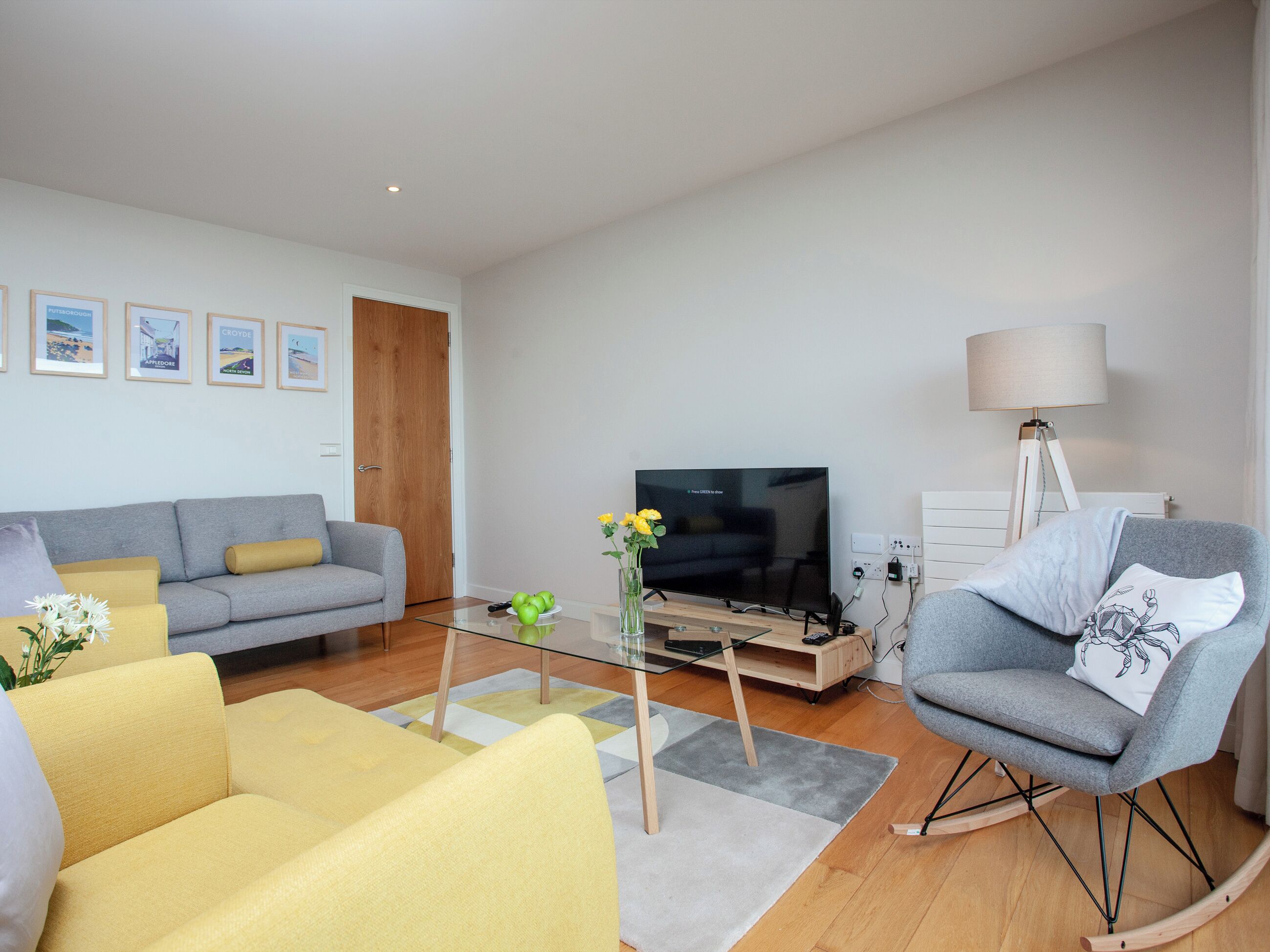 A living room with a sofa, armchairs, a coffee table, a TV, and a lamp.