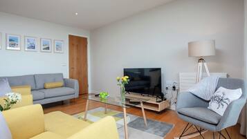 A living room with a sofa, armchairs, a coffee table, a TV, and a lamp.