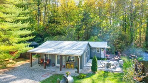 Una casa con un porche cubierto, zona de barbacoa y una pequeña terraza.