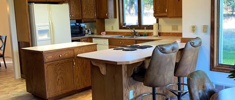 A modern kitchen with wooden cabinetry, a central island, and bar seating.