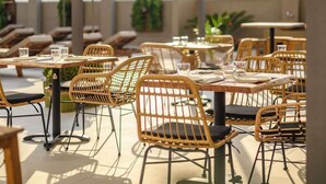 An outdoor dining area with wicker chairs and tables, some with cushions. - Nicolas Grand Suites (Kos)