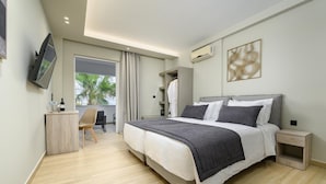 A modern hotel room with a large bed, a desk, and a TV mounted on the wall. - Nicolas Grand Suites (Kos)