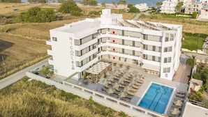 A modern hotel with multiple floors, a rooftop pool, and a view of the sea. - Nicolas Grand Suites (Kos)