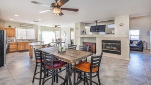 A spacious kitchen with a dining area, a fireplace, and a ceiling fan. - 777Rentals - 4BRs/3BA - Wet and Wild Convenience (Las Vegas)