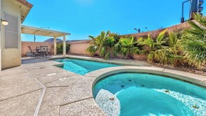 A swimming pool with a patio area, outdoor seating, and palm trees. - 777Rentals - 4BRs/3BA - Wet and Wild Convenience (Las Vegas)